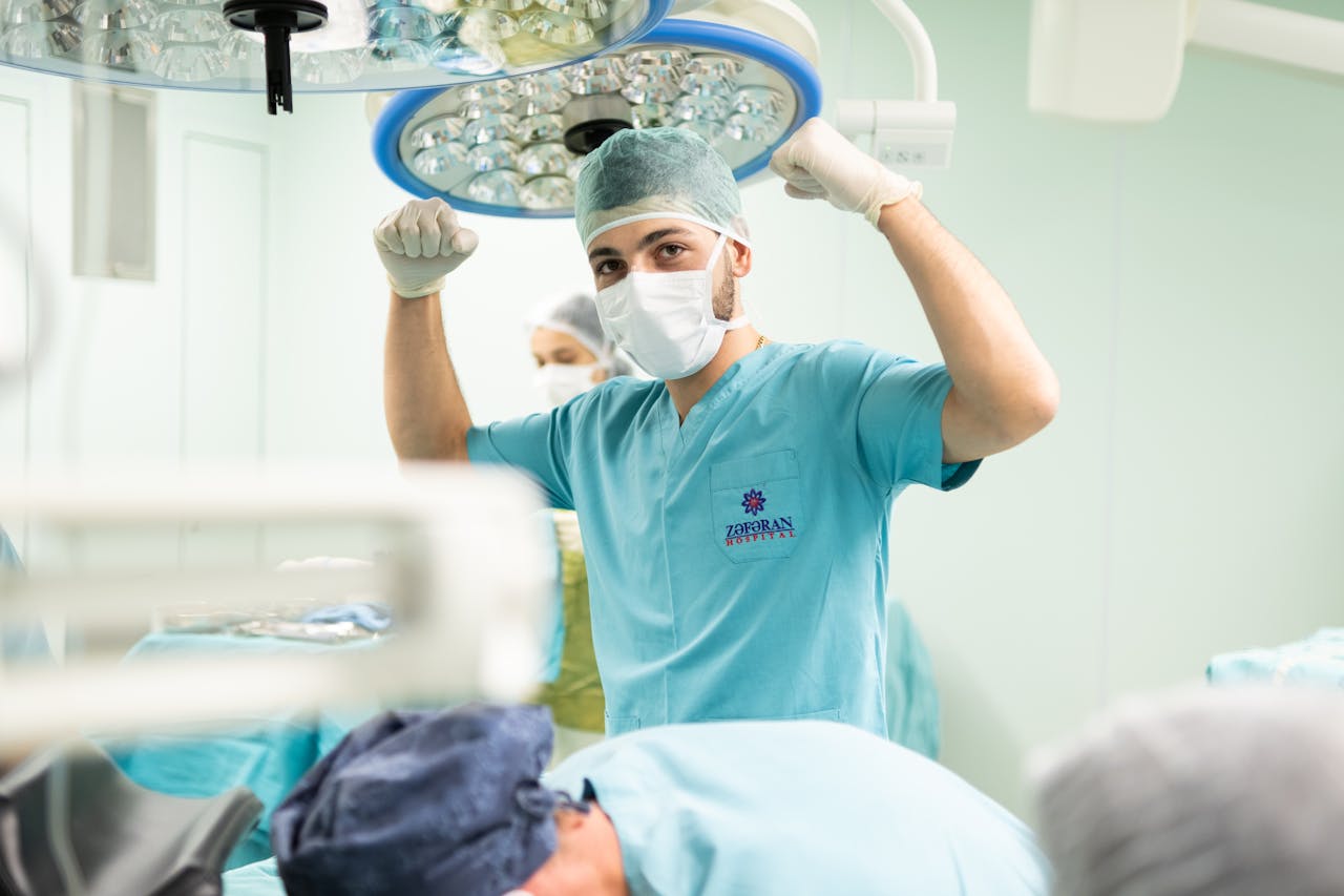 Home A surgeon in scrubs celebrates after a successful surgery in an operating room.